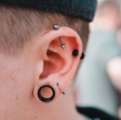 Close-up of a healthy stretched earlobe wearing a black tunnel plug