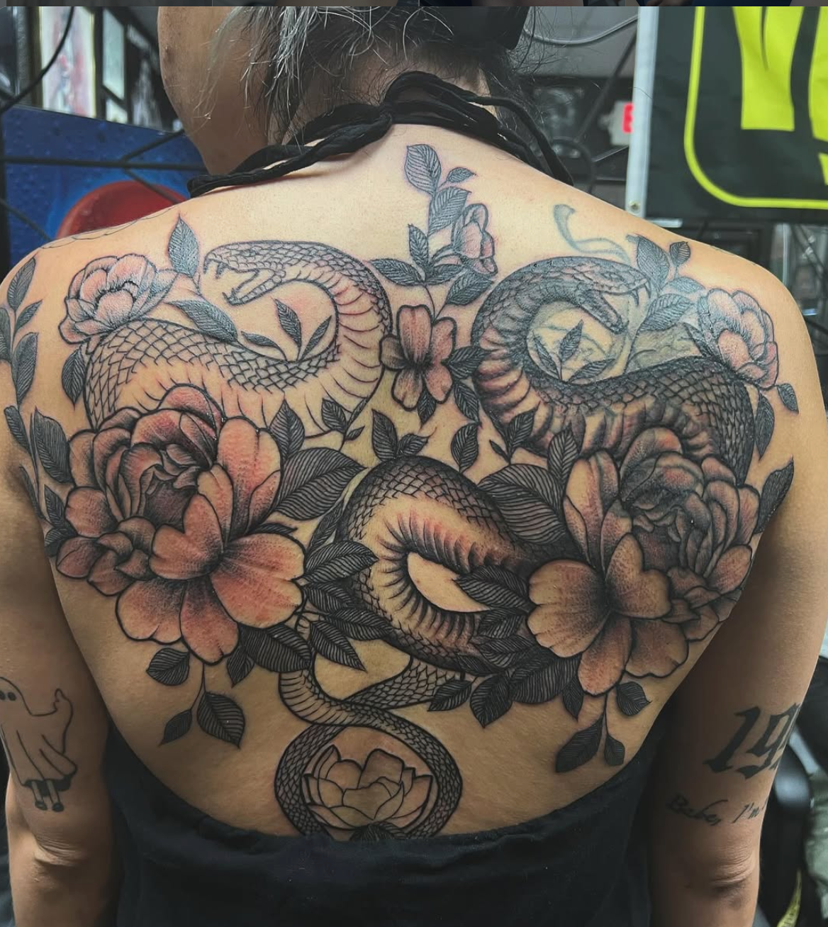 Floral and serpent female back tattoo